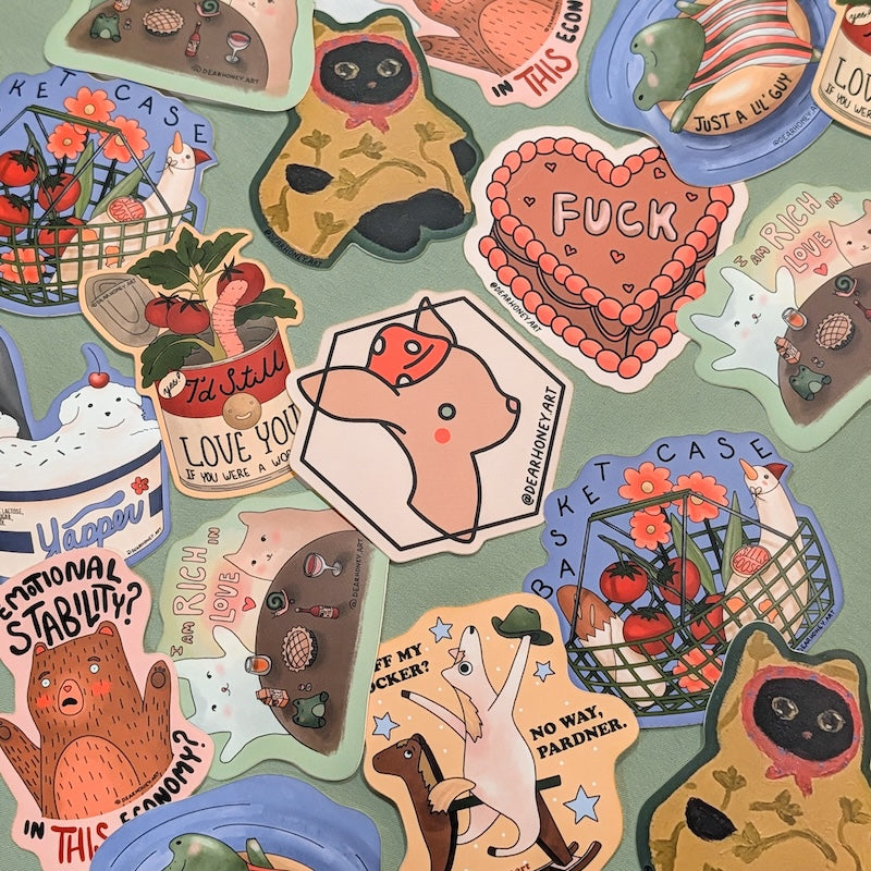 A collection of illustrated die-cut stickers arranged on a light blue-green background. The stickers feature whimsical cartoon animals, food-themed designs, and humorous text, including a heart-shaped cake that says 'FUCK', a dog wearing a red bow tie, strawberries, cherries, and a bear.